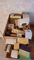 Full lot in cardboard box with various fragrance boxes and sample cases visible