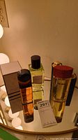 Photo of four fragrance bottles including Lancome Magie Noire, Oscar de la Renta Parfum, Marc Jacobs Apple, and Dior Addict on a reflective surface.