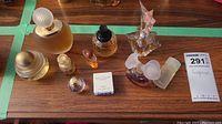 Top-down photo showing all eight fragrance bottles arranged on a wooden surface.