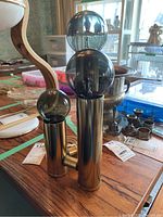 Overall view of lamp assembly showing two brass-tone cylinders and smoked globes on wood surface