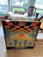 Full front view of framed painting leaning against sofa and window