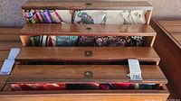 Four-tier wooden display chest filled with folded assorted scarves