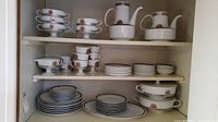 Shelf overview showing full set of Rosenthal dinnerware including cups, saucers, plates, bowls and pots