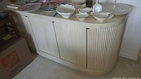 Front view showing curved tambour doors and off-white finish
