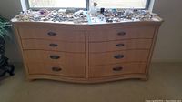 Front view of wooden dresser with six drawers and metal handles, surface scratches visible.