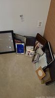 Picture frames and photo albums arranged on a carpet, showing a variety of sizes and colors.