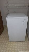 Front view of white Kenmore mini refrigerator with closed door and label showing model number.