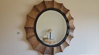 Full view of the round mirror with sunburst wooden frame hung on the wall