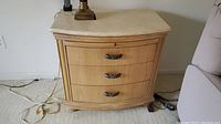 Front view of wooden nightstand with stone top, showing three drawers and metal handles.