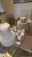 Large stacks of matte pink plate sets plus bowls and cups on glass table