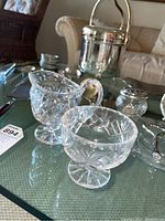 Photo of cut glass bowls and silverplate ice bucket on glass table.