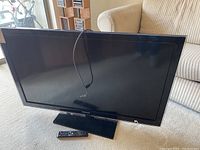 Samsung 48-inch HDTV with black frame and matching black stand, power cord visible, remote control in front.