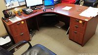 Full view of the L-shaped office desk showing curved front, dual pedestals with drawers, and laminate surface with locking hardware.