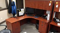 L-shaped office desk with computer monitors and office chair, showing desk surface and storage below