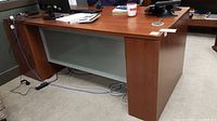 Full view of the covered particleboard office desk showing modesty panel and wood finish surface with some office items on top.