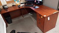 Full view of L-shaped office desk in an office cubicle showing desk top surface, two sides forming the L-shape, and open leg space beneath.