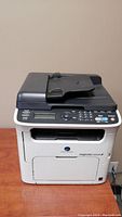 Front view of multifunction printer showing control panel and front paper outlet.