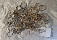 Multiple angles of assorted jewelry on fabric background showing 47 pieces mainly consisting of rings and hoop earrings in silver and gold tones.