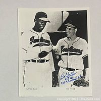 Black and white 8x10 photo showing Satchel Paige and Bob Feller in Cleveland Indians uniforms, signed by Bob Feller.