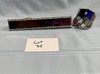 Front view of the stained glass kaleidoscope, showing the colorful long tube and hexagonal viewing end with glass beads