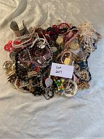 Overall shot of assorted jewelry lot on fabric background, many bead necklaces and bracelets with metal cuff and pendants