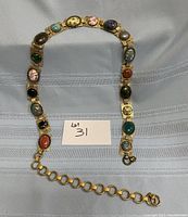 Front view of the stone cabochon belt laid flat showing the cabochon stones, gold-tone metal setting, and adjustable linked chain with clasp closure.