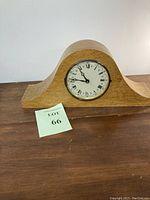Full view of the classic mantel clock with birdseye maple wood case, wooden base, and clock face with Roman numerals.