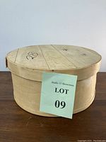 Full side view showing the round wooden box with lid and rough natural wood finish.