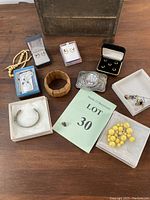 Overview image showing all jewelry pieces laid out on a wooden surface, including boxes and a card labeled Lot 30.
