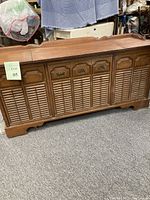 Front view of vintage wooden stereo console cabinet with decorative louvered doors and three upper drawers or compartments