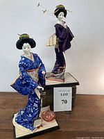 Full view of both Japanese Geisha dolls standing on wooden bases, showing detailed costumes and positioning