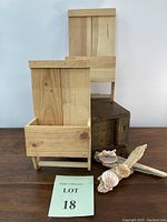 Two wooden rustic wall organizers placed on a wooden table alongside two driftwood pieces decorated with seashells.