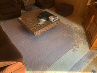 Full view of large oriental rug under coffee table and sofas, showing the lavender center and floral border pattern.