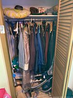 Full view inside closet showing hanging coats, shoes below, and items on shelf including hats, organizers, and blankets