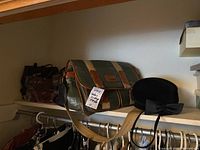 Shelf with vintage handbags, green leather-trimmed messenger bag, and black hat with bow