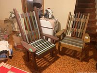 Two matching custom made wooden outdoor chairs with painted brown and green slats, placed indoors on brown carpet.