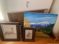 View of all artworks showing one landscape painting and several framed sketches and prints.