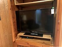 Samsung TV model LN40C610N1F placed in wooden cabinet, front view showing screen and stand.