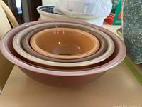 Side view of four nested Pyrex mixing bowls showing varying colors and sizes.