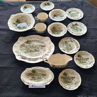 Full set image of 12-piece china set with plates, bowls, teacups, platter, and gravy boat on dark background.