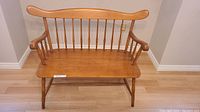 Front view of maple bench showing spindle back, crest rail and seat