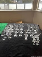 Photo showing varied crystal glasses on black cloth, different shapes and sizes, some with chips visible