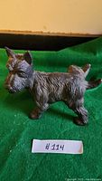 Front and side views of the metal Scottish Terrier figurine on a green cloth background.
