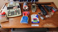 Photo of Canon CP-1219 adding machine, Staples rubber bands, manual sharpener, two-hole punch, stapler, USB mouse, USB cable, USB flash drive on wooden table