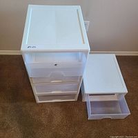 Five white plastic stackable drawers shown stacked together and one drawer removed and placed beside the unit to show depth and drawer style.