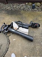 Toro and Jobmate leaf blowers and vacuum, laid on concrete surface showing collection bag, blower tubes and vacuum tube.
