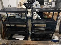 Two black shelving units standing side by side, showing their slotted shelves and general structure.