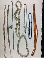 Top-down photo of seven assorted costume jewellery necklaces laid out on a white surface