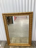 Front view of large rectangular mirror with ornate gold frame.