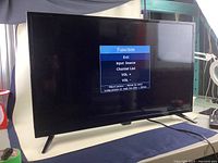 Front view of the Insignia 32 inch LED TV powered on displaying function menu on screen.